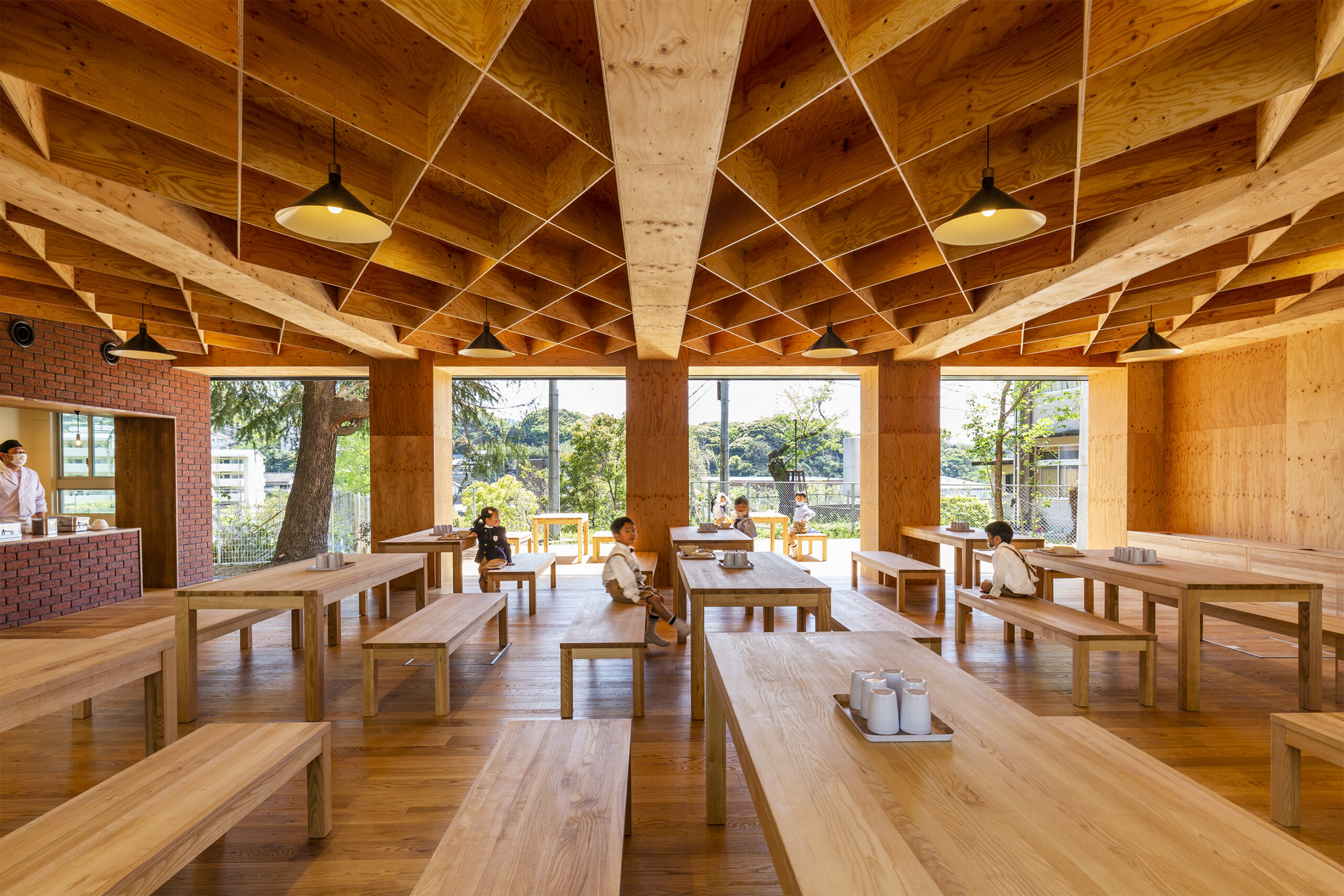 A shot from the dining hall of KB Primary and Secondary School, highlighting its magnificent wooden floors, furniture, and cladding, all adorned in warm hues of natural wood.