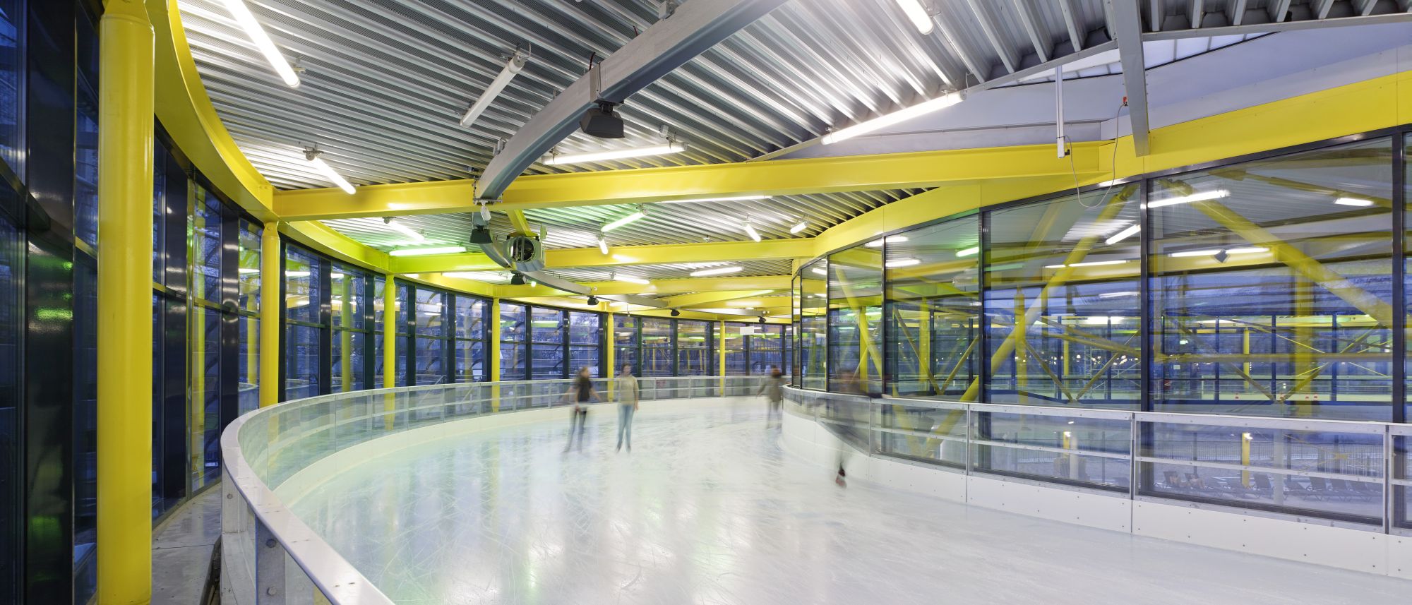 A view of the ice skating track around the central area of the building, complemented by striking yellow structural elements.