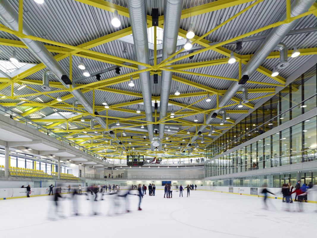 A view of the large ice skating rink, complemented by striking yellow structural elements.