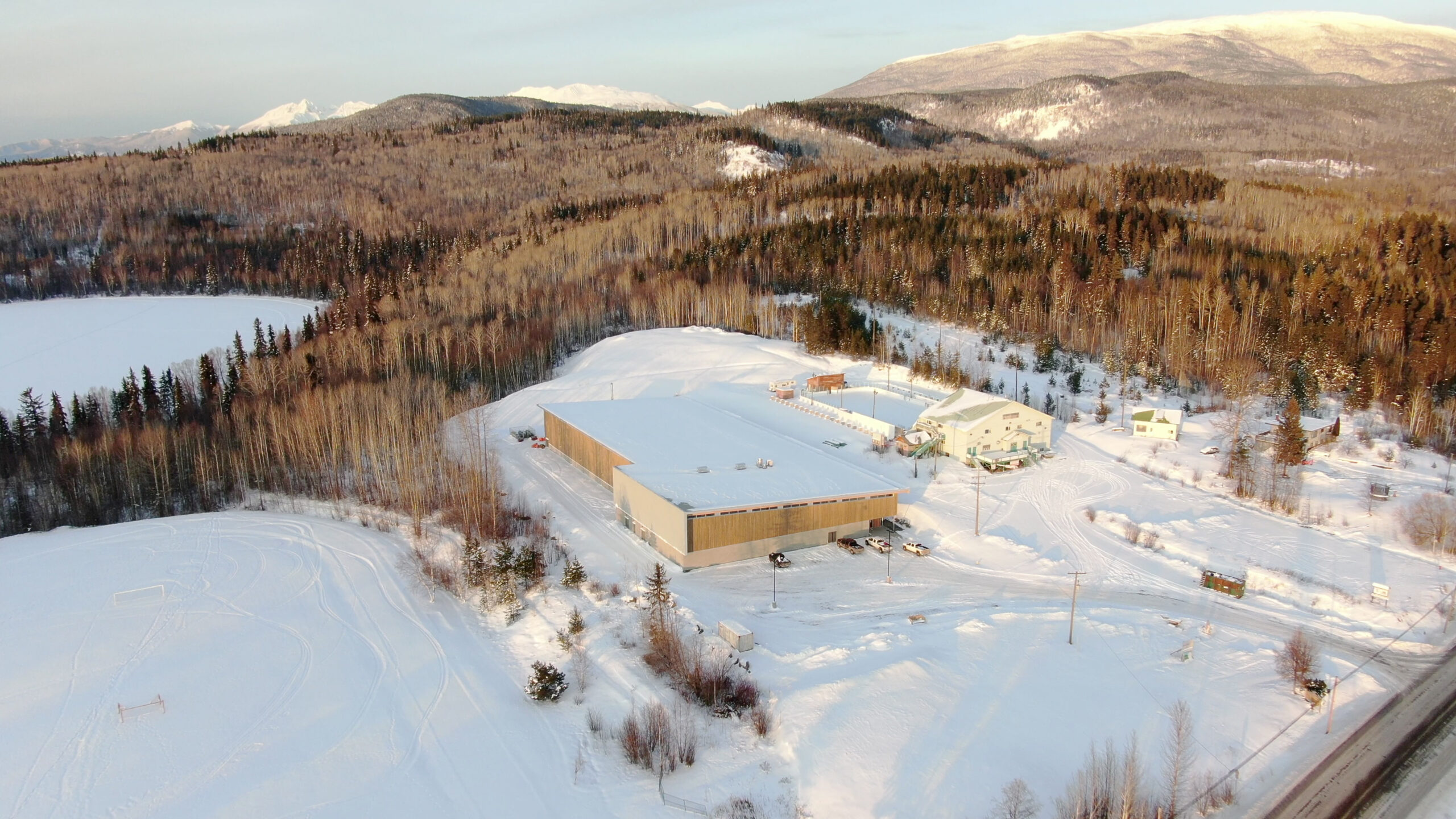 A semi-aerial view showcases the Upper Skeena Recreation Center y blending into the snow-capped mountain landscape