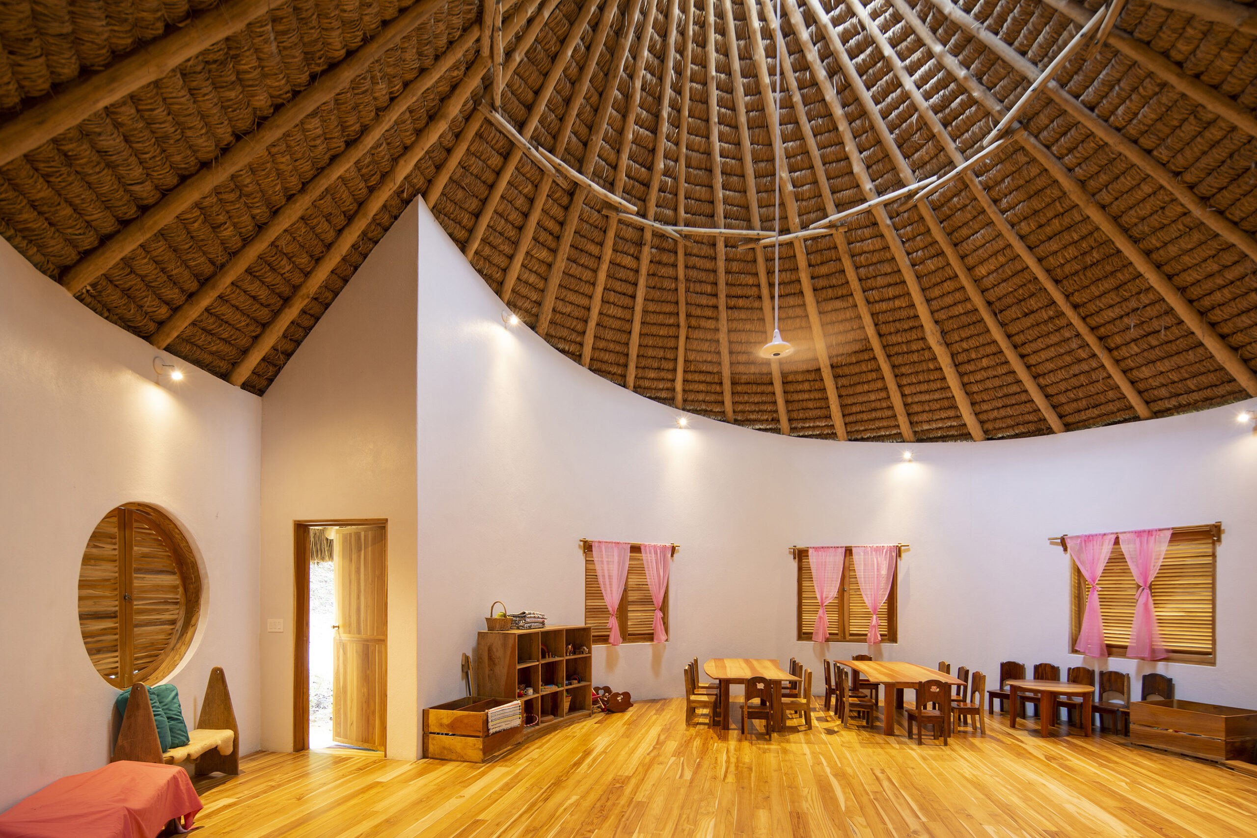 An interior shot of the circular classrooms, featuring the unique snail spiral roof design that incorporates beautiful wooden elements, adding to the space's organic and natural aesthetic.